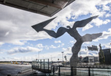 Statue av mann som kaster et papirfly på Gardermoen flyplass i Norge.