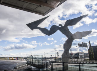 Statue av mann som kaster et papirfly på Gardermoen flyplass i Norge.