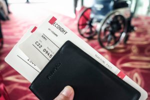 Closeup of boarding passes and passport at airport terminal boarding gate with a wheelchair in the