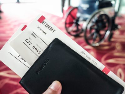Closeup of boarding passes and passport at airport terminal boarding gate with a wheelchair in the