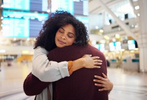 Couple, hug and embracing goodbye at airport for travel, trip or flight in farewell for long distan