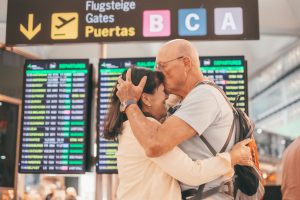 Couple of senior people hugging and goodbye in airport area for arriving or departing trip