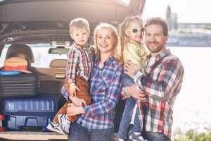 Togetherness is a very important ingredient to family life. Family stands near the car, looking at