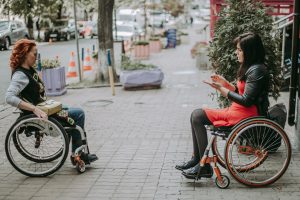 Two girls in wheelchairs travel through the central streets.