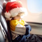 Little child wearing Santa Claus hat is traveling by an airplane