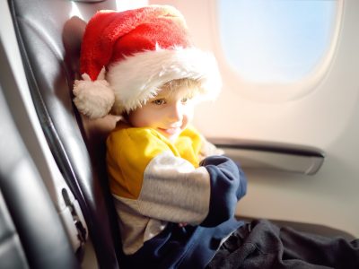 Little child wearing Santa Claus hat is traveling by an airplane