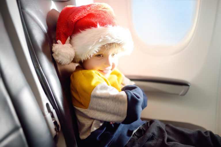 Little child wearing Santa Claus hat is traveling by an airplane